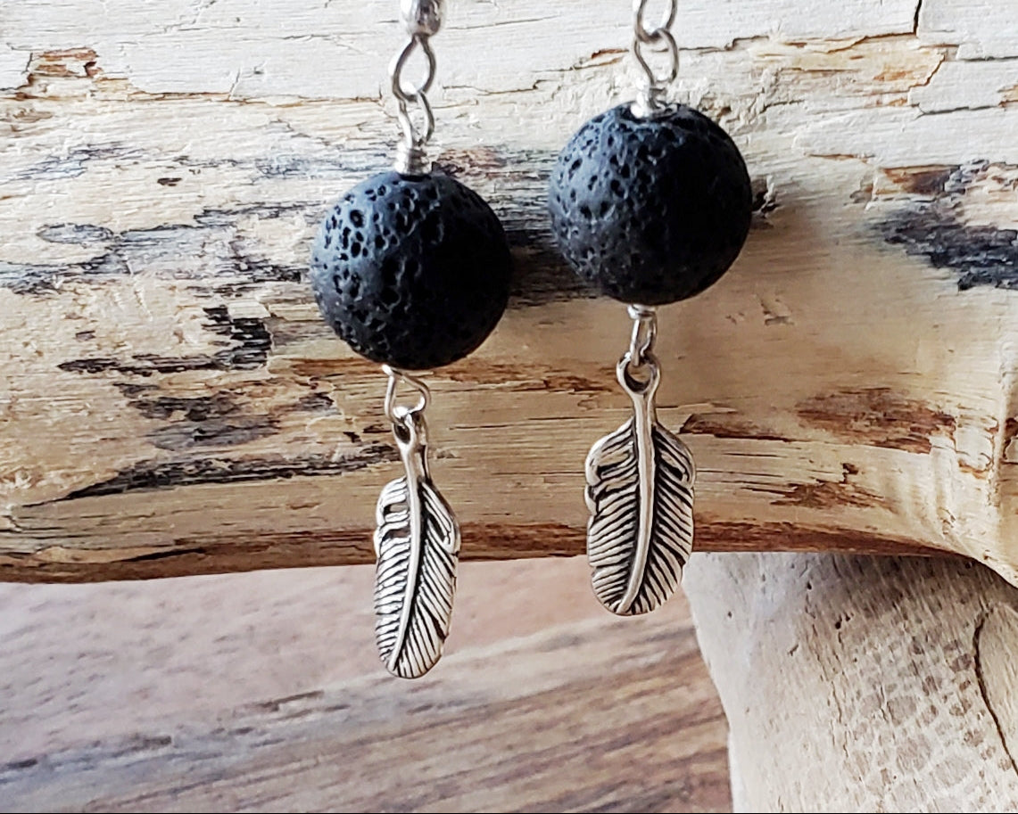 Long Feather Lava stone Earrings made with solid Sterling Silver Feather pendants and black Lava Stone on french earrings hooks displayed on beach wood 