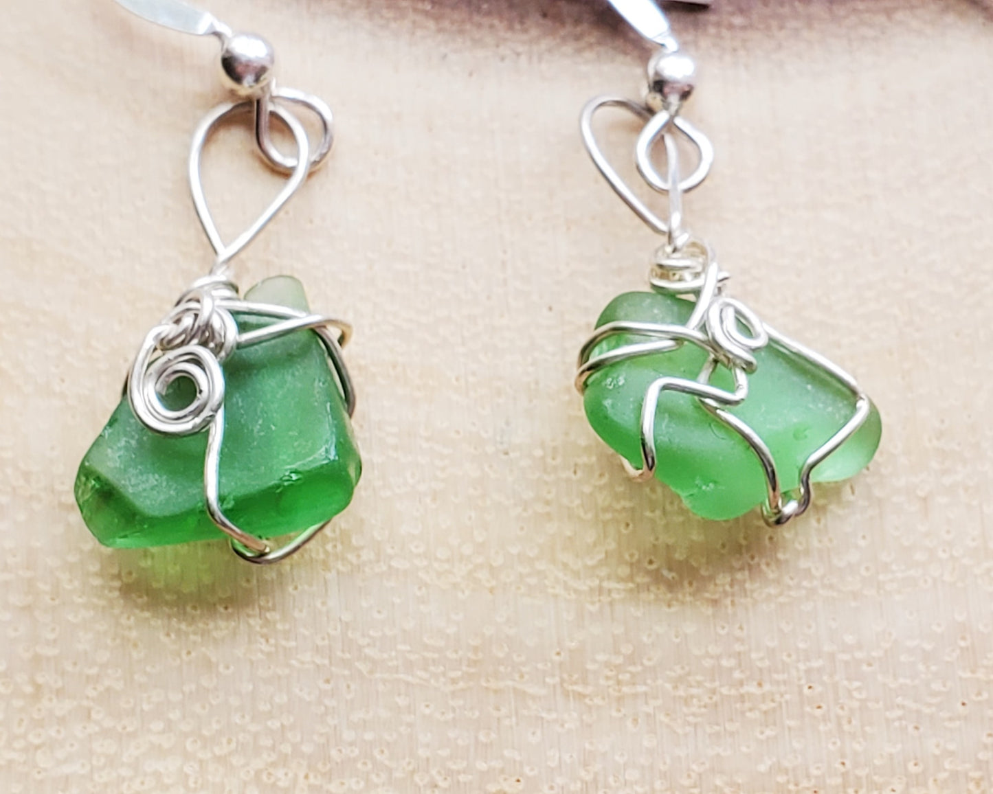 Peaceful Green Sea Glass, Beach Glass Earrings, Sterling Silver Wire Wrapped Green Beach Glass Dangle Earrings displayed on wood