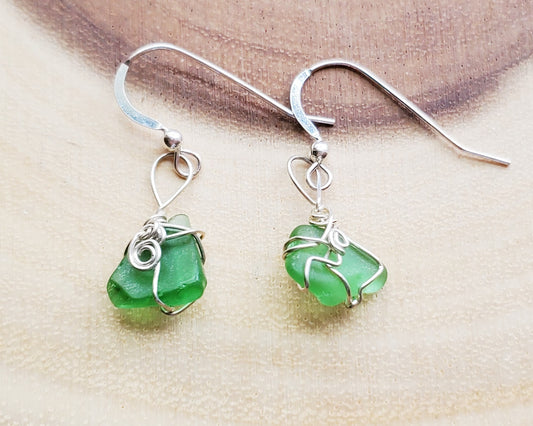 Peaceful Green Sea Glass, Beach Glass Earrings, Sterling Silver Wire Wrapped Green Beach Glass Dangle Earrings displayed on wood