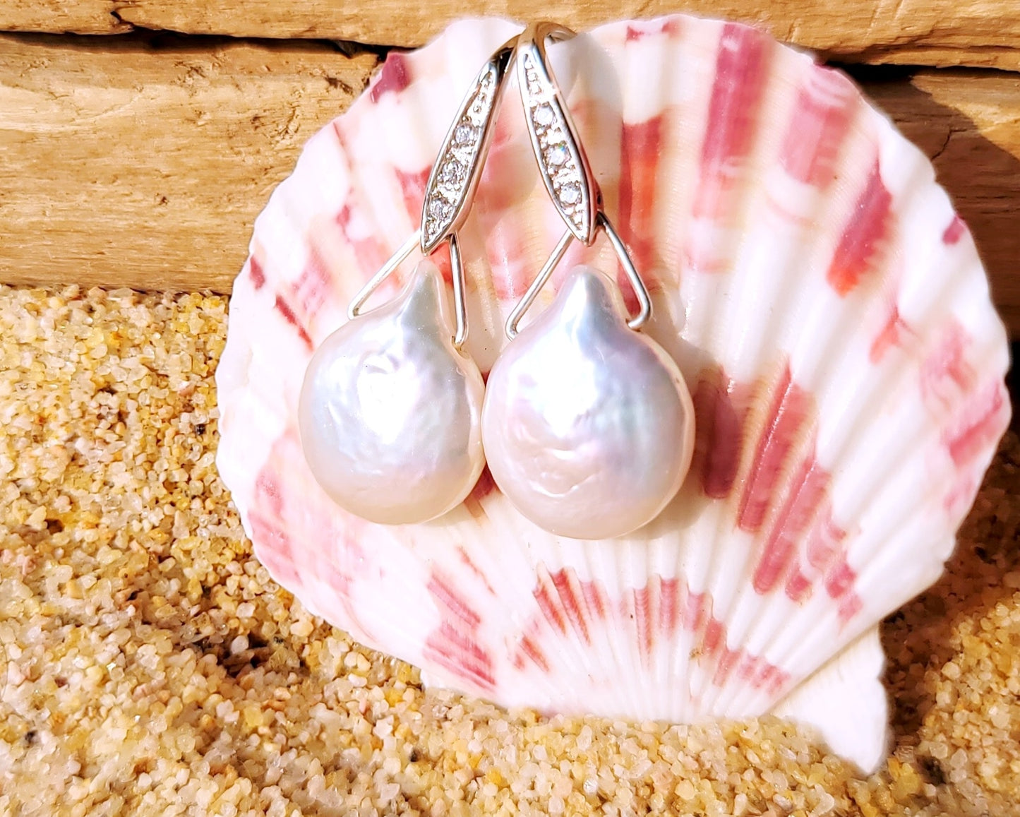 Large White Baroque Pearl Earrings, Large white, drop shaped, almost coin shaped pearls danglin from a Cubic Zirconia encrusted French earrings hooks, dangling from a pink and white sea shell 